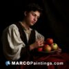 A boy seated next to a basket with apples