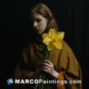 A woman in a brown robe holding a daffodil